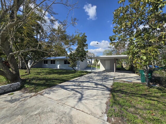 ranch-style house featuring a carport and a front lawn