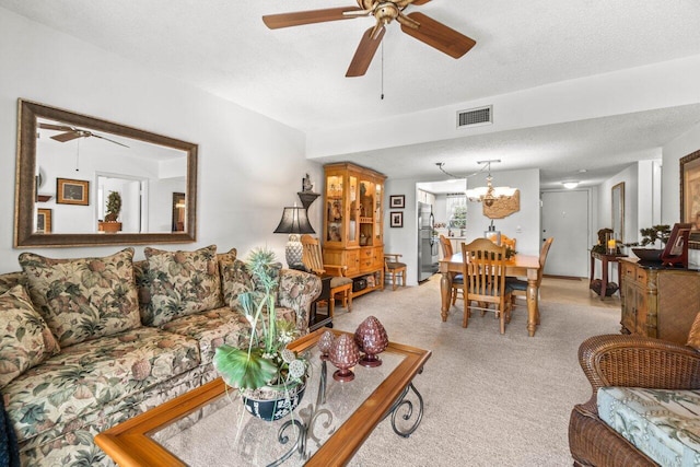 carpeted living room featuring ceiling fan with notable chandelier and a textured ceiling