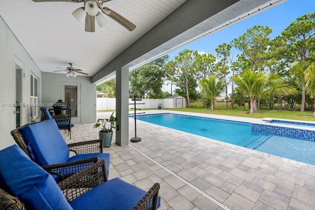 view of swimming pool featuring a storage shed, ceiling fan, outdoor lounge area, a patio area, and an in ground hot tub