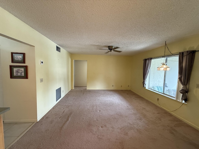 unfurnished room with ceiling fan, light colored carpet, and a textured ceiling