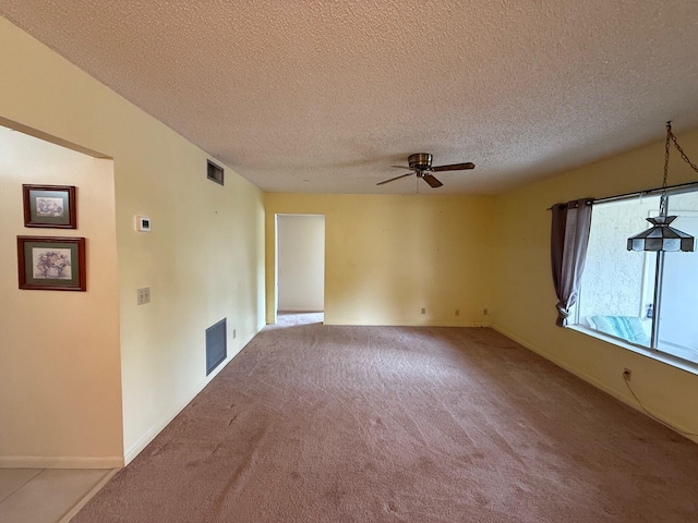 carpeted empty room featuring baseboards, visible vents, a textured ceiling, and ceiling fan