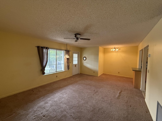 carpeted spare room with visible vents, baseboards, a textured ceiling, and ceiling fan with notable chandelier