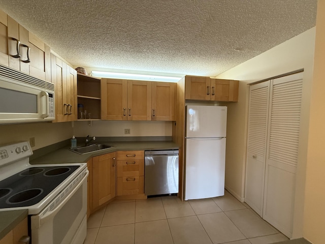 kitchen with sink, white appliances, light tile patterned floors, and a textured ceiling