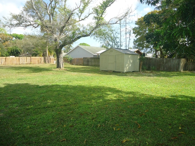 view of yard featuring a fenced backyard, an outdoor structure, and a storage shed