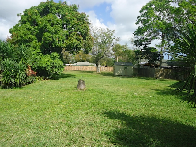 view of yard with a storage shed, a fenced backyard, and an outbuilding