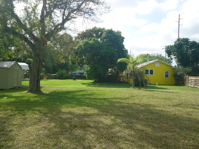 view of yard with a storage shed, an outbuilding, and fence