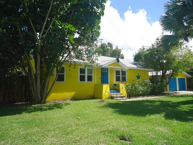 view of front of property featuring metal roof, a front lawn, and stucco siding