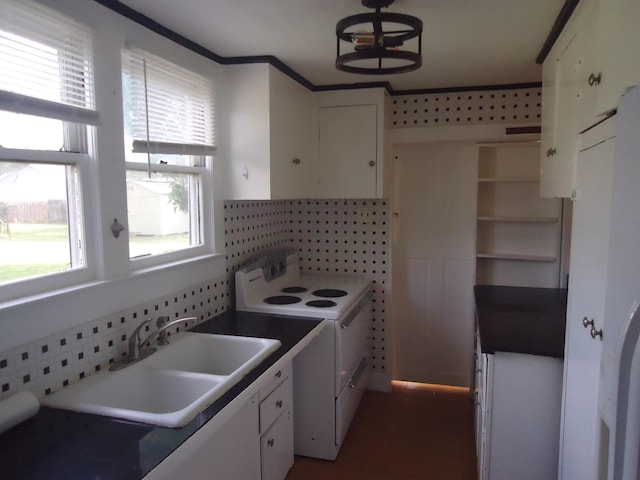 kitchen featuring plenty of natural light, white electric range, white cabinetry, and a sink