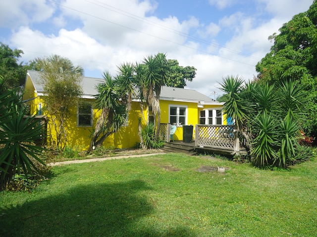 rear view of property featuring stucco siding, a lawn, and a wooden deck