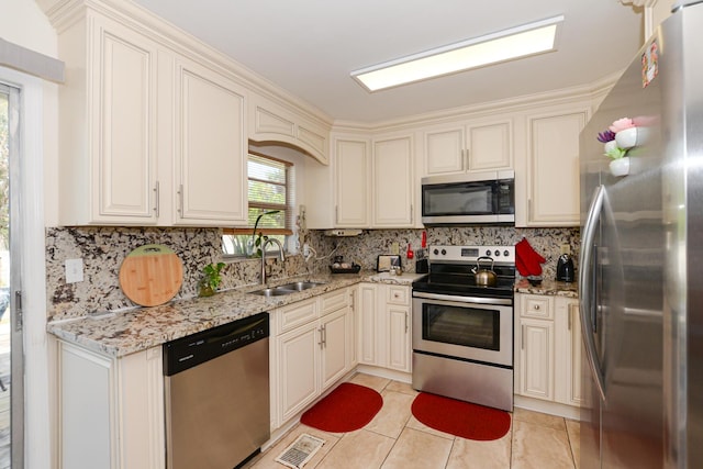 kitchen with light stone counters, stainless steel appliances, sink, and backsplash