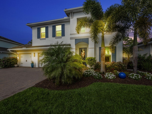 view of front of property featuring decorative driveway, a garage, and stucco siding