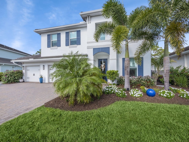 view of front of house with stucco siding, decorative driveway, a front yard, and an attached garage