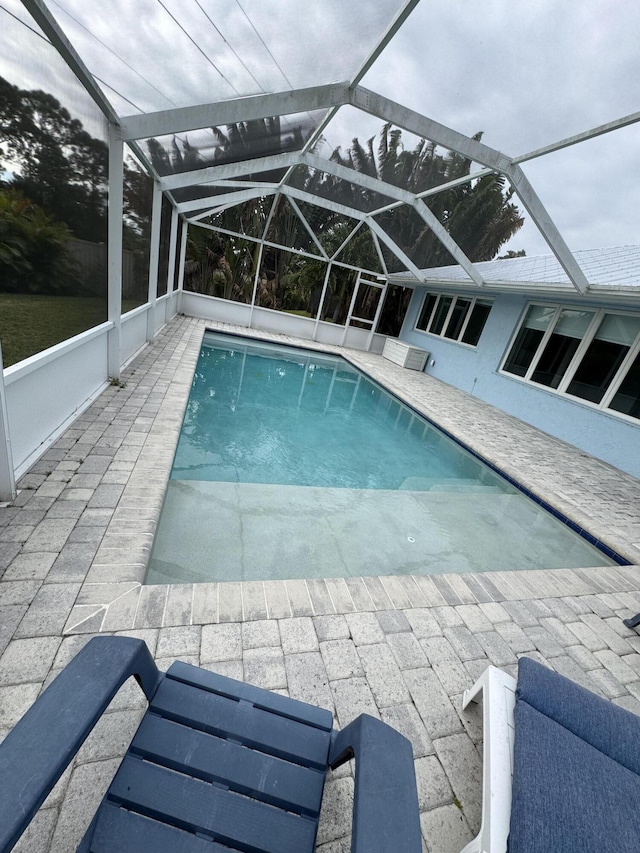 view of pool featuring glass enclosure and a patio area