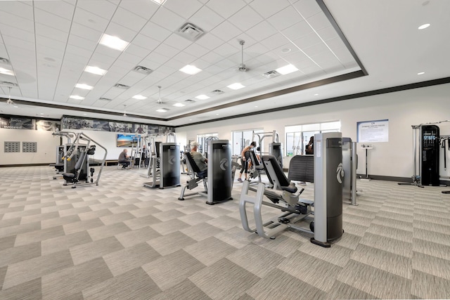 workout area featuring light carpet, visible vents, baseboards, a raised ceiling, and crown molding