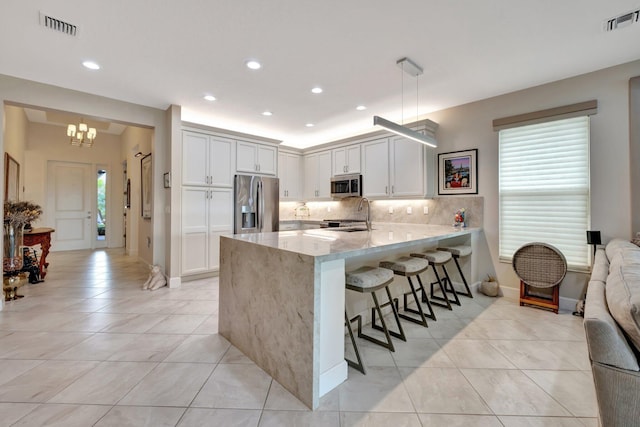 kitchen featuring a peninsula, visible vents, appliances with stainless steel finishes, and tasteful backsplash