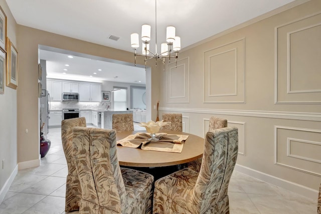 dining area featuring an inviting chandelier, light tile patterned floors, visible vents, and a decorative wall