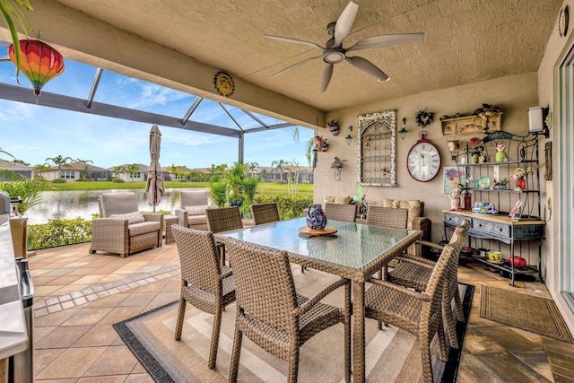 view of patio with glass enclosure, outdoor dining area, a water view, and a ceiling fan