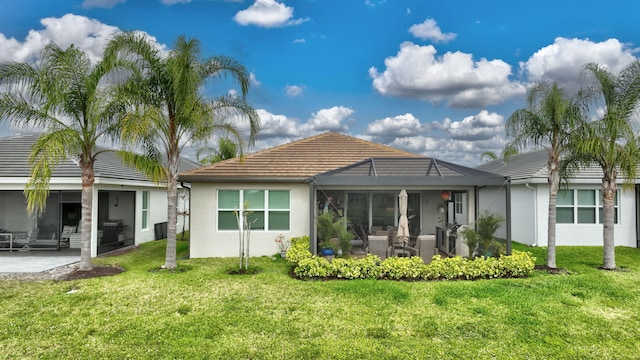 rear view of house with stucco siding, a tile roof, a patio, and a yard