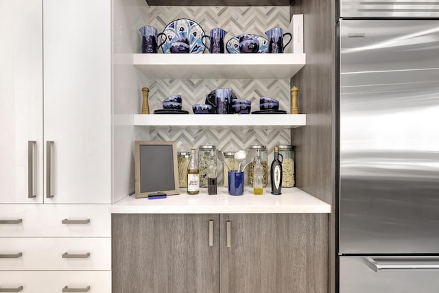 bar featuring stainless steel built in refrigerator and backsplash