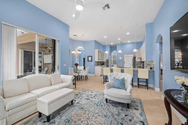 tiled living room with ceiling fan with notable chandelier