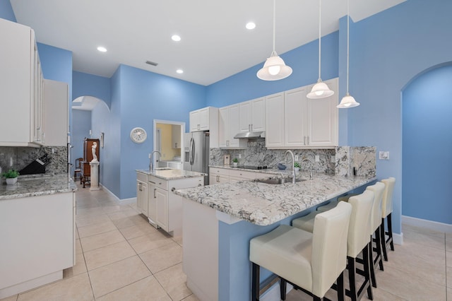 kitchen with sink, hanging light fixtures, white cabinets, stainless steel fridge with ice dispenser, and kitchen peninsula