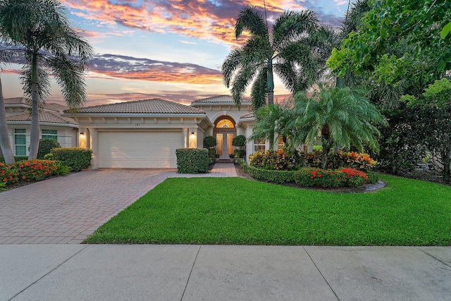 mediterranean / spanish-style home featuring a garage and a lawn