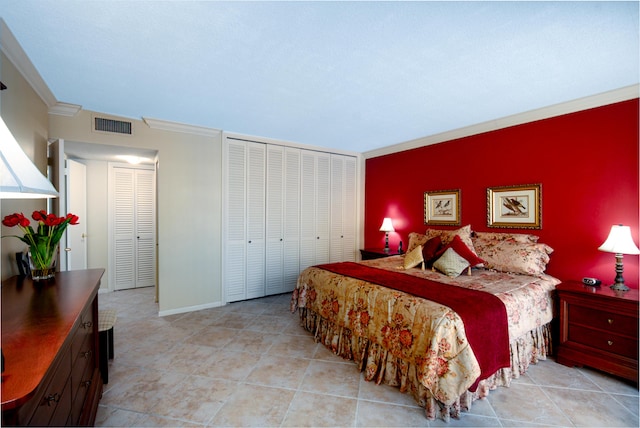 bedroom with an accent wall, visible vents, baseboards, a closet, and crown molding