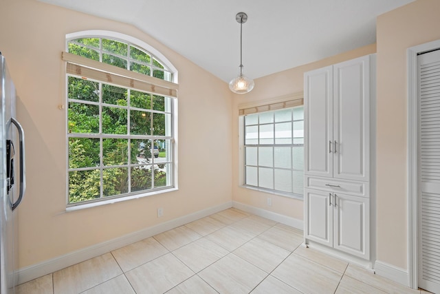 unfurnished dining area with vaulted ceiling and light tile patterned floors