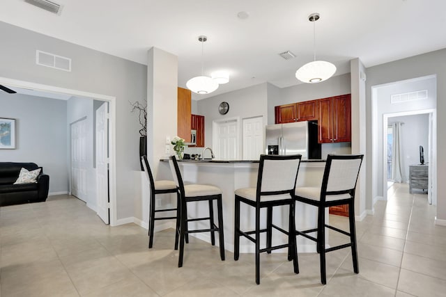 kitchen with pendant lighting, stainless steel fridge with ice dispenser, kitchen peninsula, and a breakfast bar