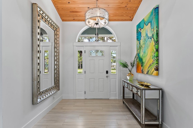 foyer entrance with a notable chandelier, vaulted ceiling, wooden ceiling, and light wood-type flooring