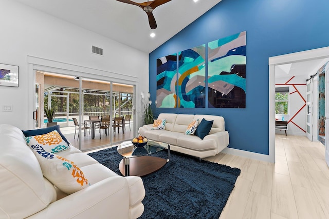 living room with high vaulted ceiling, a barn door, and ceiling fan