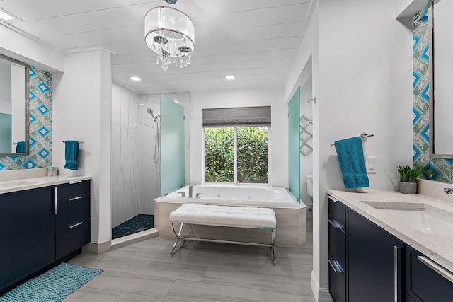 bathroom featuring plus walk in shower, vanity, and an inviting chandelier