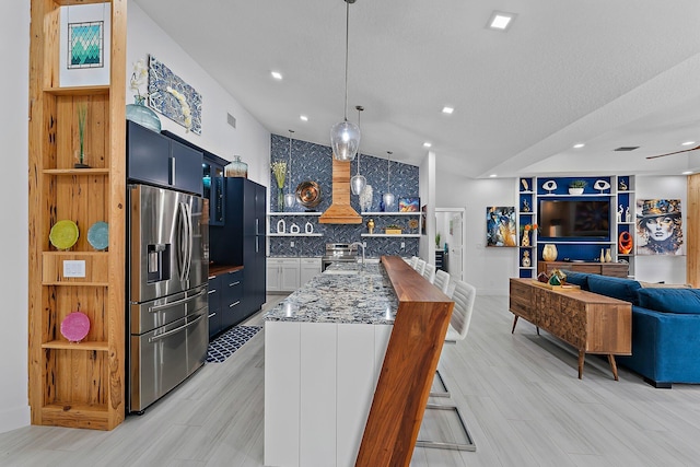 kitchen featuring blue cabinetry, a breakfast bar area, appliances with stainless steel finishes, pendant lighting, and dark stone counters