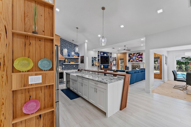 kitchen with white cabinetry, decorative light fixtures, light stone counters, and light hardwood / wood-style flooring