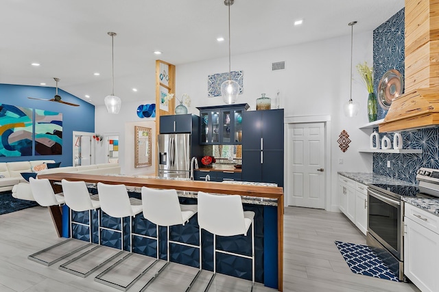 kitchen with stainless steel appliances, high vaulted ceiling, pendant lighting, and a kitchen bar