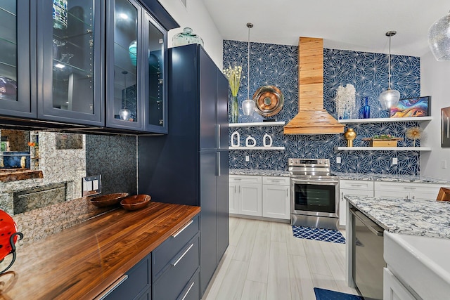 kitchen with pendant lighting, butcher block countertops, decorative backsplash, custom exhaust hood, and stainless steel appliances