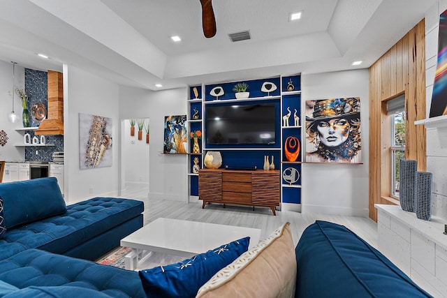 living room with light hardwood / wood-style flooring and a raised ceiling