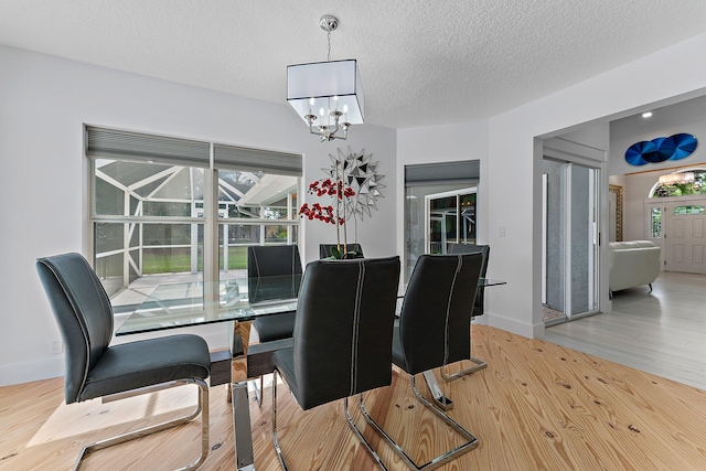 dining area featuring a textured ceiling, a notable chandelier, and light hardwood / wood-style floors