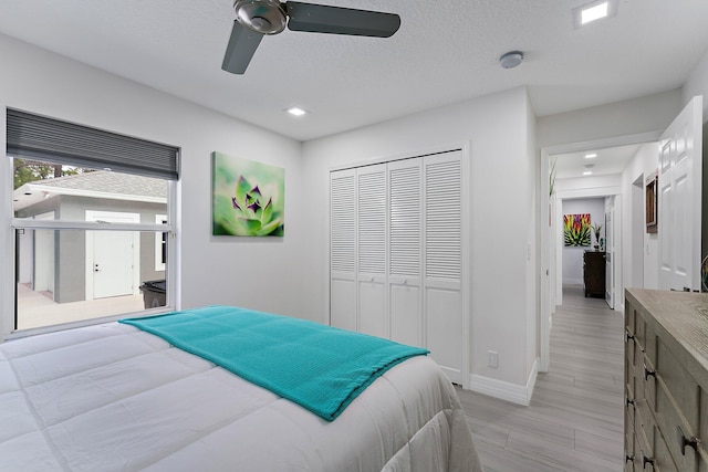 bedroom featuring light hardwood / wood-style floors, a textured ceiling, ceiling fan, and a closet