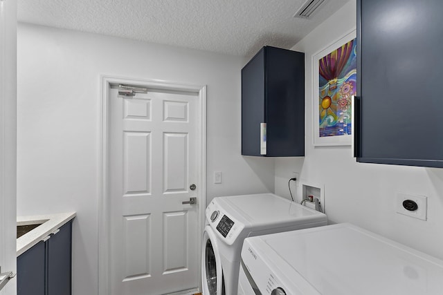 laundry area featuring cabinets, washer and clothes dryer, and a textured ceiling