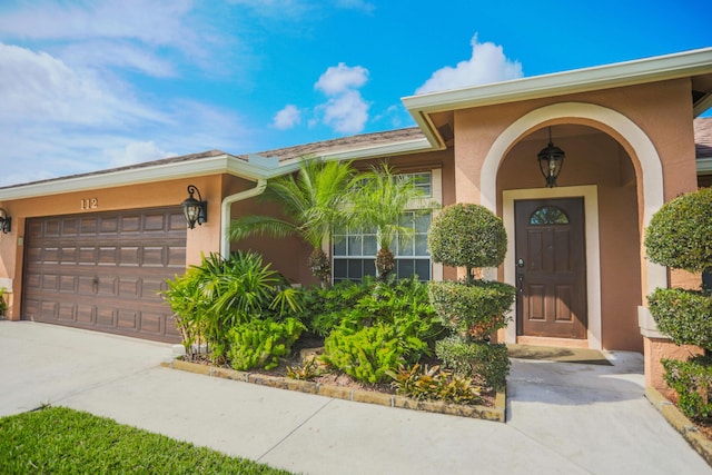 property entrance featuring stucco siding, a garage, and concrete driveway