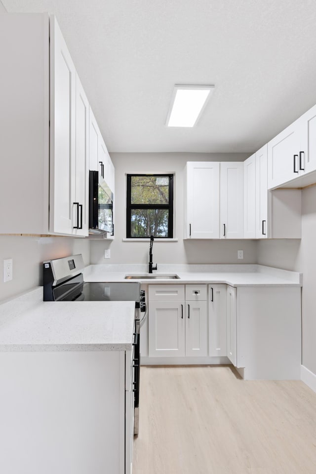 kitchen featuring sink, stainless steel electric stove, light hardwood / wood-style floors, and white cabinets