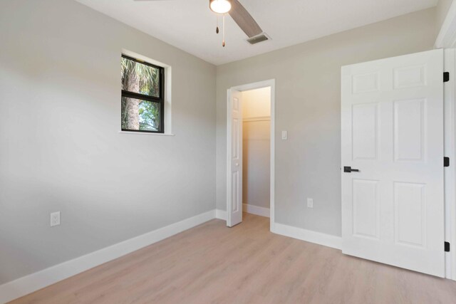 unfurnished bedroom with ceiling fan, a closet, and light wood-type flooring