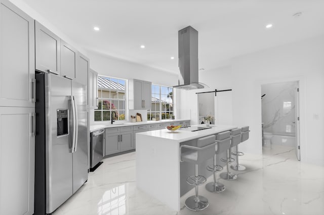 kitchen featuring appliances with stainless steel finishes, a breakfast bar, island exhaust hood, a center island, and a barn door