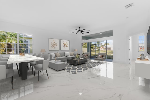 living room featuring a wealth of natural light, visible vents, marble finish floor, and a ceiling fan