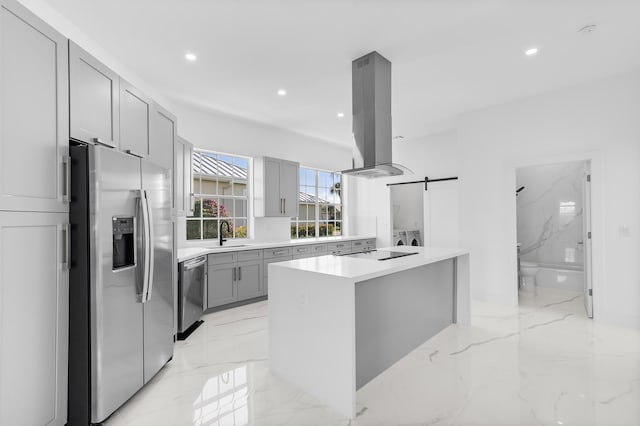 kitchen with a kitchen island, island range hood, sink, stainless steel appliances, and a barn door