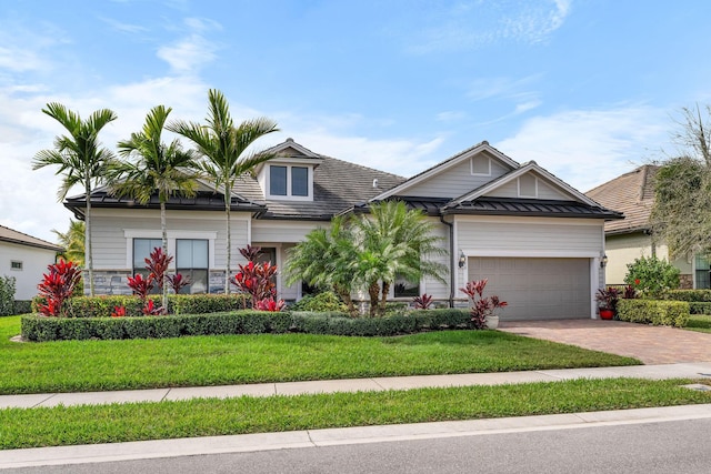 view of front of property with a front lawn, a standing seam roof, decorative driveway, an attached garage, and metal roof