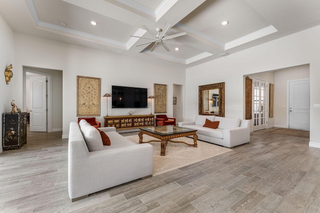 living room with ceiling fan, light wood-type flooring, and a towering ceiling