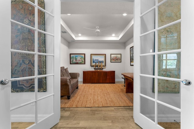 office space featuring visible vents, a tray ceiling, recessed lighting, french doors, and wood finished floors