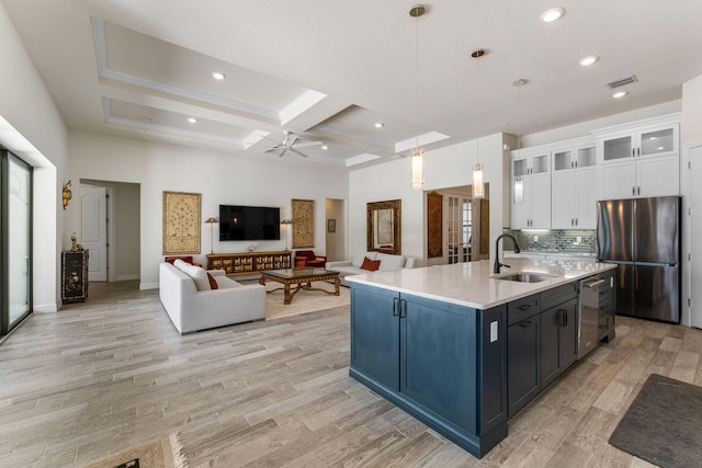 kitchen with visible vents, ceiling fan, freestanding refrigerator, white cabinets, and a sink